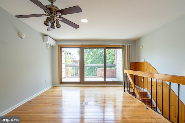 spare room featuring a wall unit AC, light wood-style floors, and baseboards