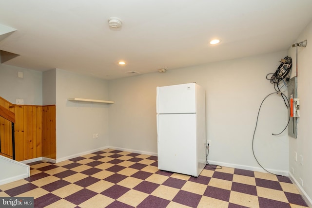 basement with freestanding refrigerator, baseboards, light floors, and recessed lighting