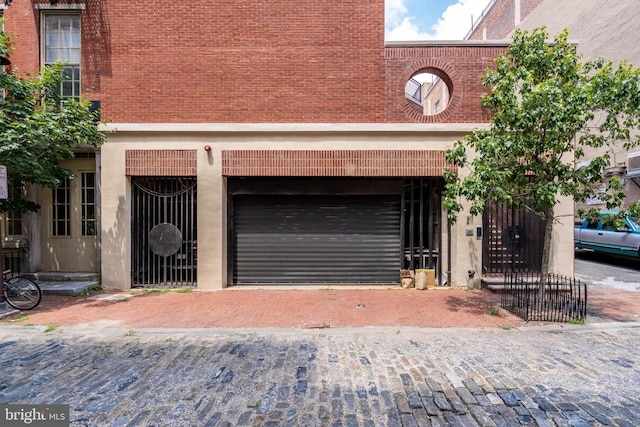 view of front of home with a garage, brick siding, and decorative driveway