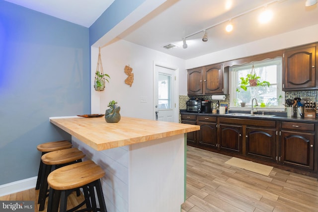 kitchen featuring tasteful backsplash, light wood-type flooring, and visible vents