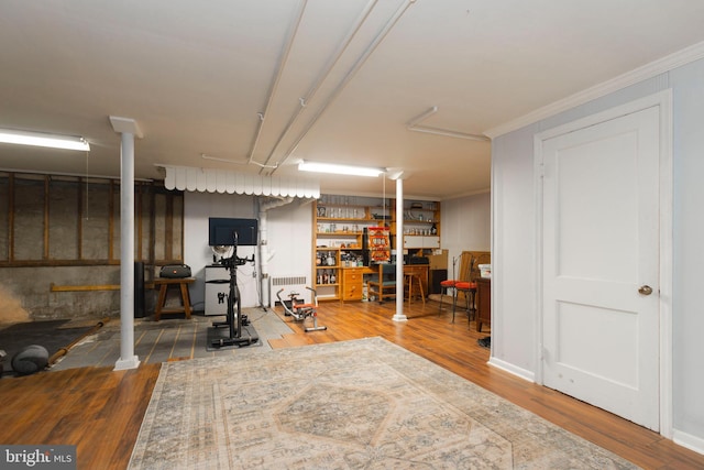 exercise area featuring radiator heating unit, wood finished floors, and crown molding