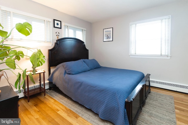 bedroom featuring light wood finished floors and baseboard heating