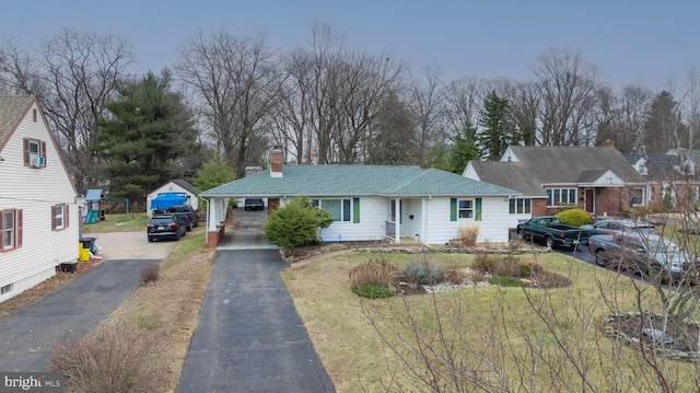 view of front facade featuring aphalt driveway and a chimney