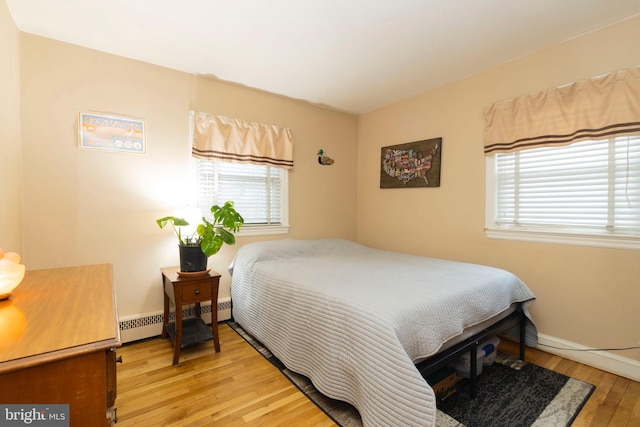 bedroom featuring light wood-type flooring, a baseboard radiator, and baseboards