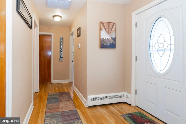 entryway featuring baseboard heating, light wood-type flooring, visible vents, and baseboards