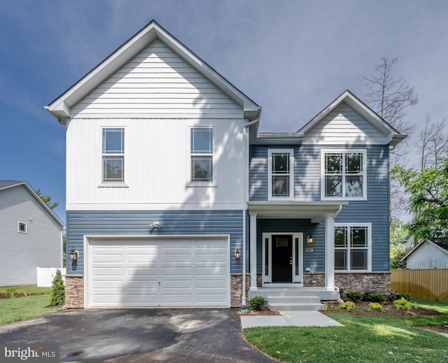 view of front of home with aphalt driveway, an attached garage, fence, stone siding, and a front lawn