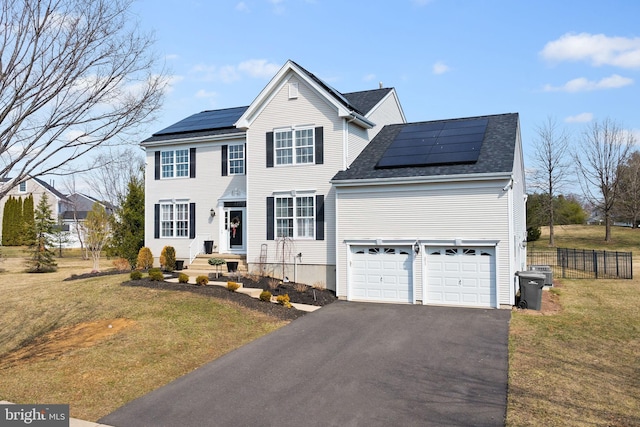 view of front of property featuring driveway, solar panels, a front yard, and fence