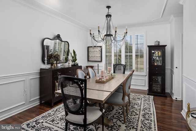 dining room with a notable chandelier, dark wood finished floors, crown molding, and a decorative wall