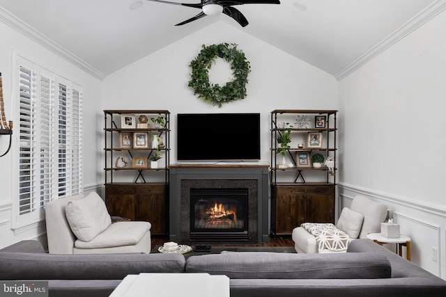 living area featuring a glass covered fireplace, wainscoting, crown molding, and lofted ceiling