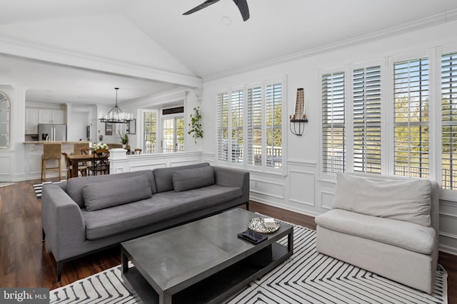 living area with a wainscoted wall, lofted ceiling, dark wood-style floors, and ceiling fan with notable chandelier