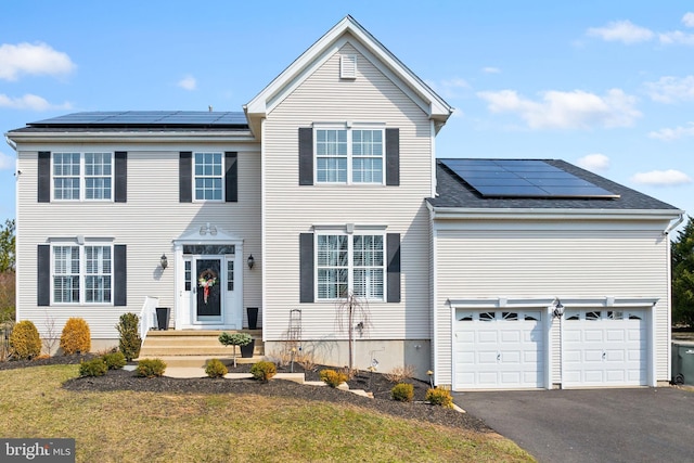 traditional home with aphalt driveway, a garage, solar panels, and a front lawn