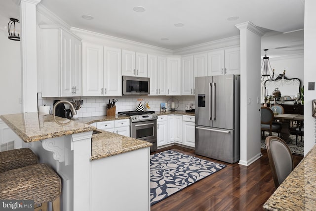 kitchen featuring white cabinets, appliances with stainless steel finishes, and a peninsula