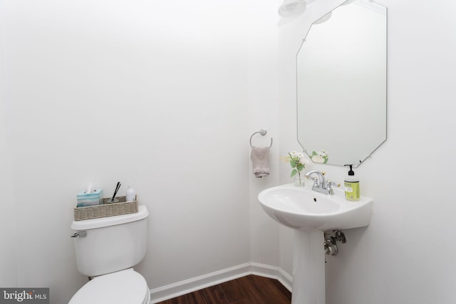 half bathroom featuring toilet, wood finished floors, and baseboards