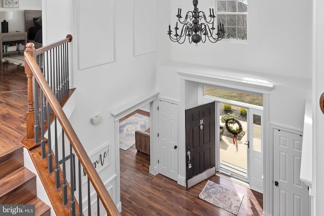 foyer featuring a notable chandelier, a high ceiling, dark wood-style floors, and stairs