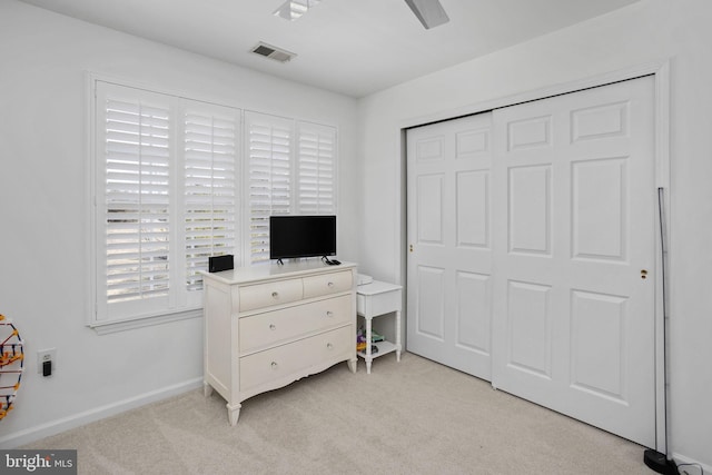 bedroom with visible vents, a closet, baseboards, light colored carpet, and ceiling fan