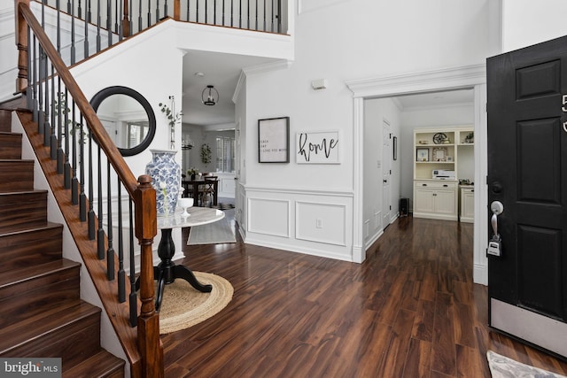 entryway featuring ornamental molding, stairs, a towering ceiling, and wood finished floors