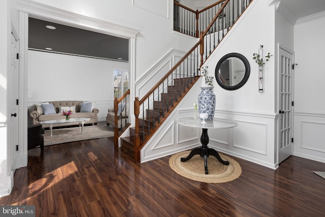 stairs featuring wainscoting, wood finished floors, crown molding, and a decorative wall