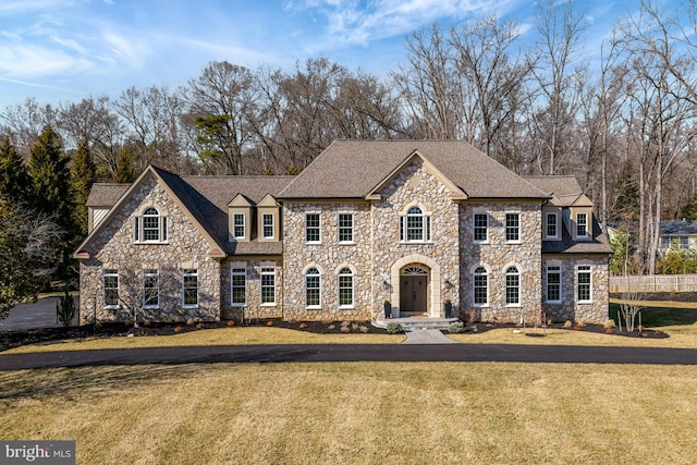 view of front of home with roof with shingles and a front yard