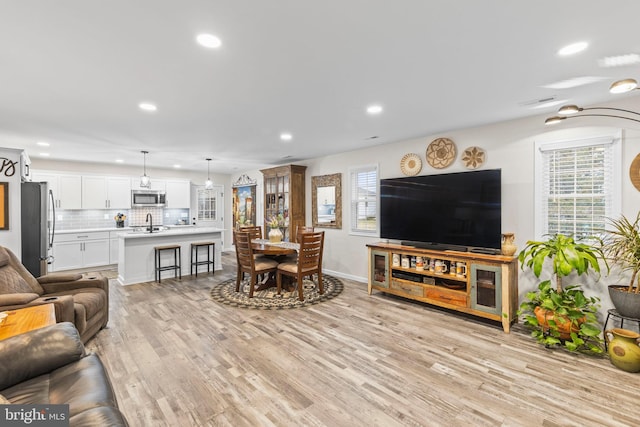 living room with light wood finished floors, baseboards, a wealth of natural light, and recessed lighting