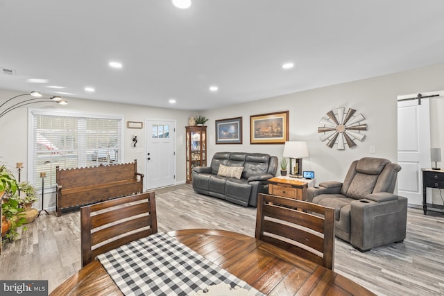 living room featuring light wood-type flooring, a barn door, and recessed lighting