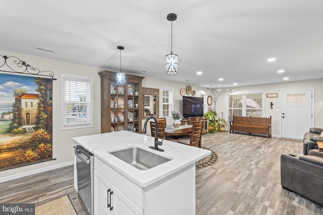 kitchen with a sink, visible vents, light wood-style floors, open floor plan, and stainless steel dishwasher