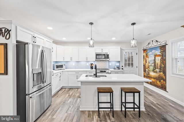 kitchen with stainless steel appliances, white cabinets, and backsplash