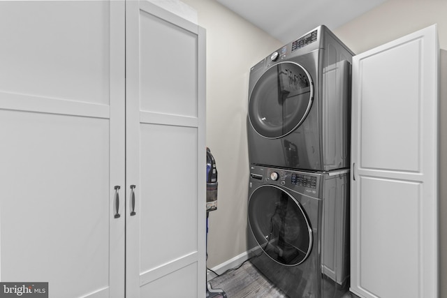 laundry room featuring stacked washing maching and dryer, laundry area, and wood finished floors