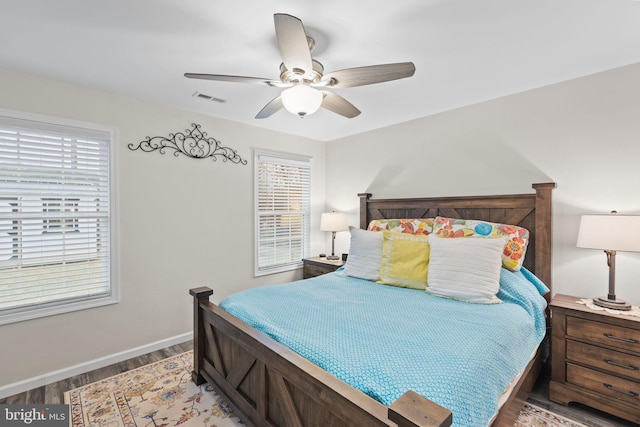 bedroom featuring wood finished floors, visible vents, baseboards, and multiple windows