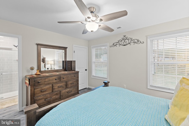 bedroom featuring connected bathroom, multiple windows, visible vents, and wood finished floors