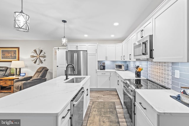 kitchen with a sink, white cabinets, appliances with stainless steel finishes, backsplash, and light wood finished floors