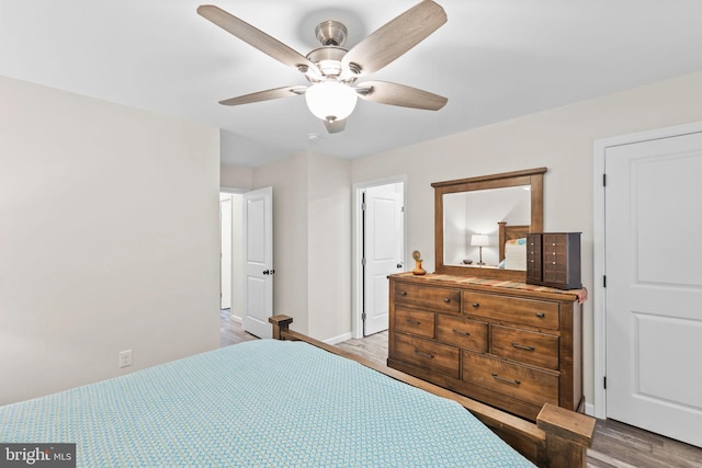 bedroom with ceiling fan, wood finished floors, and baseboards