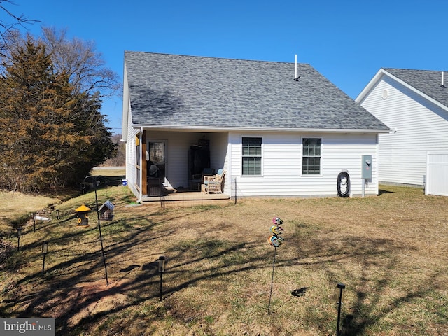 back of house with a shingled roof and a lawn