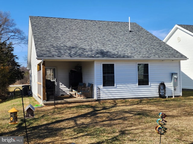 back of property with a yard, roof with shingles, and a patio