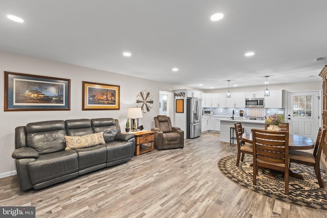 living area featuring recessed lighting, visible vents, light wood-style flooring, and baseboards