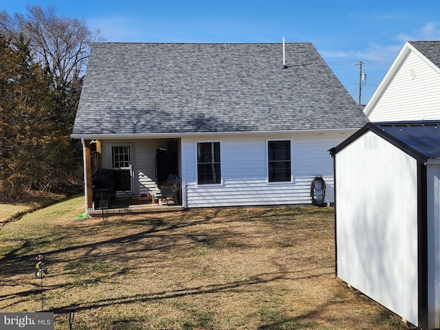 rear view of property with a shingled roof, a storage unit, a yard, a patio area, and an outdoor structure