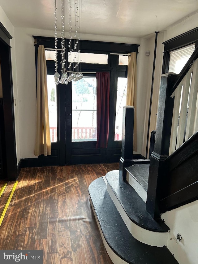 entrance foyer with baseboards, stairway, wood finished floors, and a notable chandelier