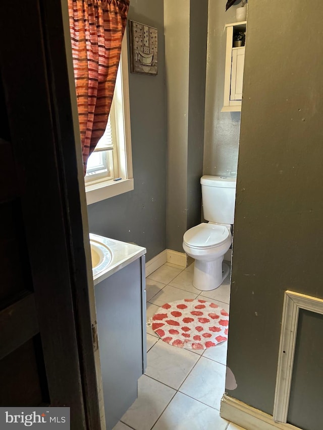 bathroom with toilet, vanity, baseboards, and tile patterned floors