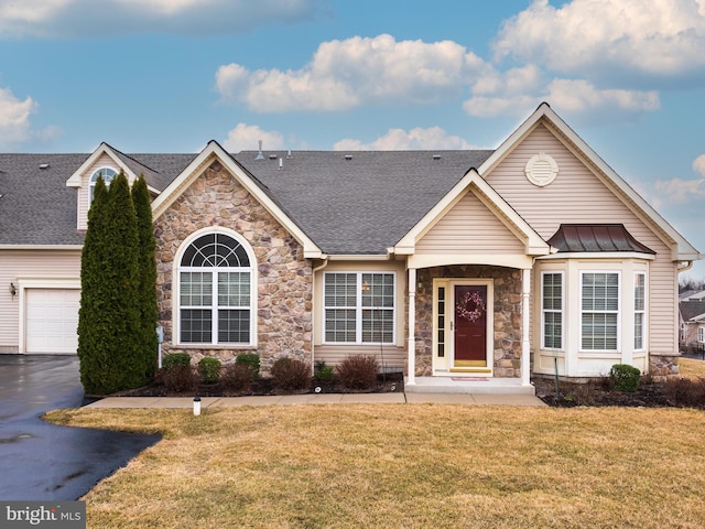 single story home with metal roof, aphalt driveway, a garage, a standing seam roof, and a front yard