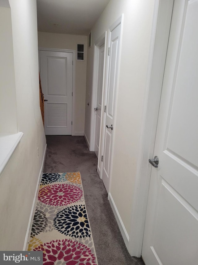 corridor with carpet flooring, visible vents, and baseboards