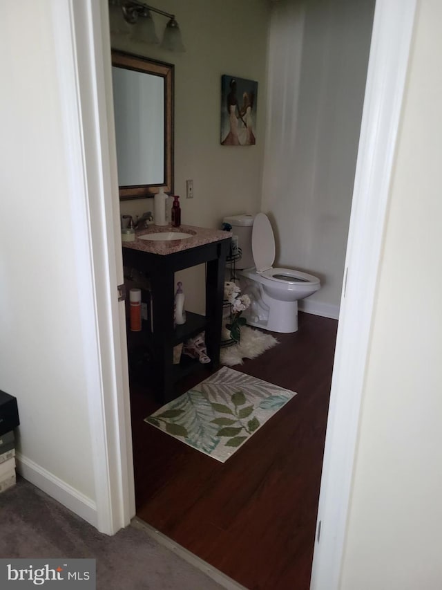 bathroom featuring toilet, baseboards, and vanity