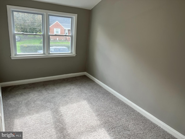 carpeted empty room featuring baseboards