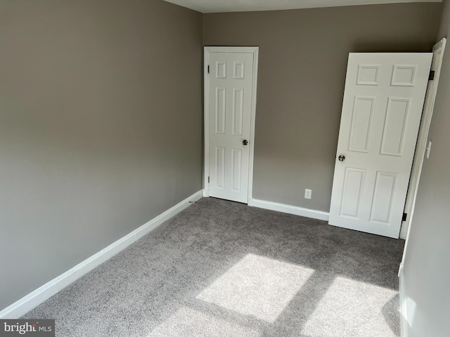 unfurnished bedroom with dark colored carpet and baseboards