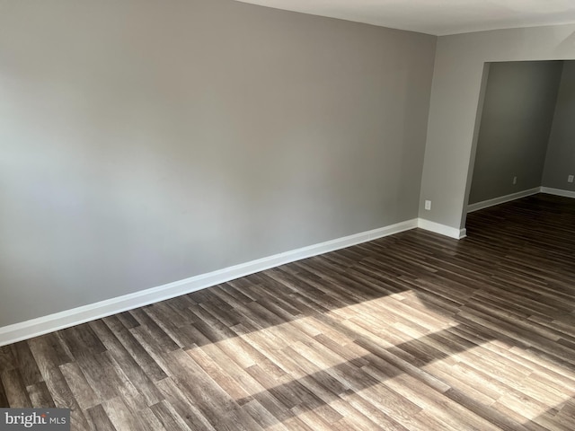 spare room featuring baseboards and dark wood finished floors