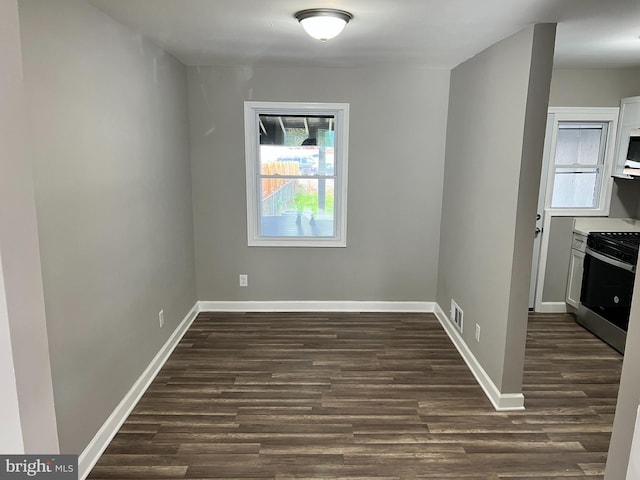 unfurnished dining area featuring dark wood-style flooring, visible vents, and baseboards