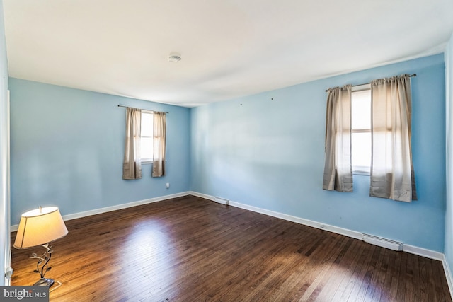 spare room featuring wood-type flooring and baseboards