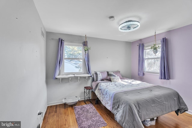 bedroom featuring wood finished floors, visible vents, and baseboards