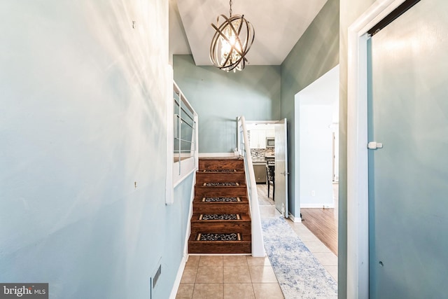 hall featuring light tile patterned floors, baseboards, visible vents, stairway, and a notable chandelier