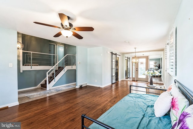 living area with stairs, a barn door, wood finished floors, baseboards, and ceiling fan with notable chandelier