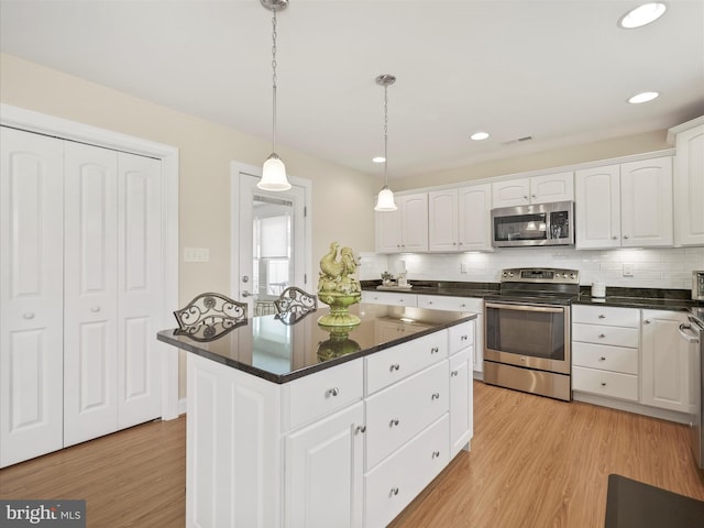 kitchen with stainless steel appliances, white cabinets, decorative backsplash, and light wood finished floors