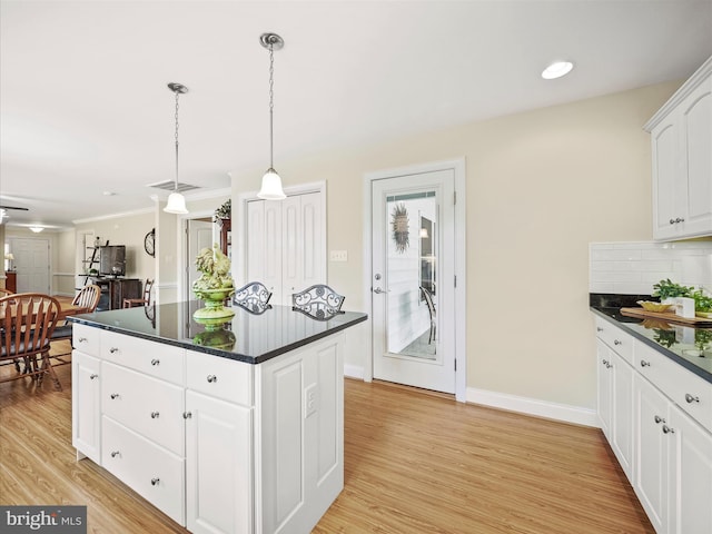 kitchen featuring dark countertops, light wood-style flooring, a kitchen island, and backsplash